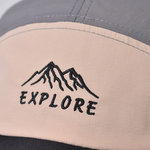 Close-up of mountain peak embroidery and EXPLORE text on a cotton outdoor baseball cap