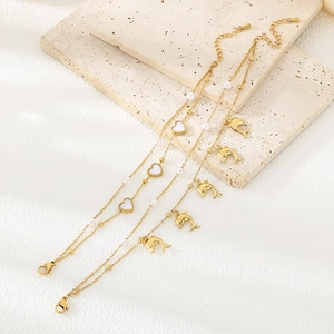 Detail of gold heart and dolphin charms with pearls on stainless steel bracelets