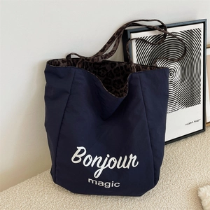 Detail of dark blue tote bag with leopard print lining and Bonjour magic text