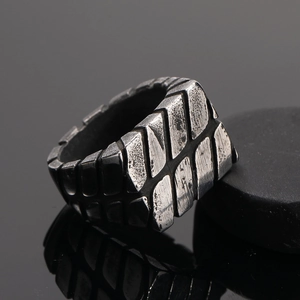 Macro detail of men's industrial titanium steel ring with textured tire tread patterns
