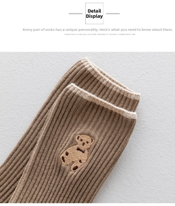 Close-up of brown ribbed mid-calf sock featuring detailed cute bear embroidery