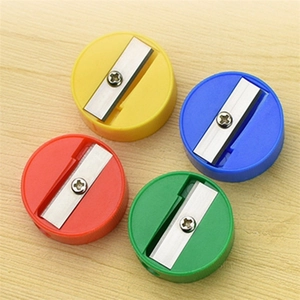 Top view of four colorful plastic pencil sharpeners on a light wood grain surface