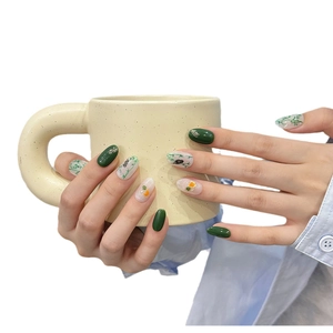 Handmade press-on nails with green bamboo ink art design on a long oval shape