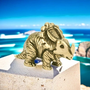 Detailed view of miniature bronze triceratops figurine with realistic skin texture on rock