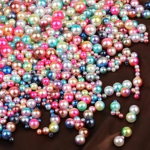 Colorful 4-10mm gradient faux pearl beads with metallic luster on dark fabric