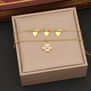 Detail of double-layer gold star necklace with crystal beads and clover pendant on a gift box