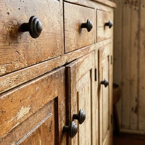 Vintage round cast iron cabinet knob with hammered texture on rustic wood furniture