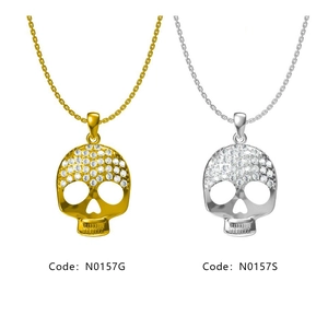 Détail de pendentifs tête de mort dorés et argentés avec strass sur fond blanc épuré