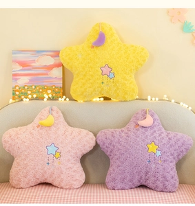 Detailed view of plush star pillows in yellow, pink, and purple with moon pendants