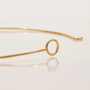 Detailed close-up of 18K gold-plated stainless steel curved necklace component on white surface