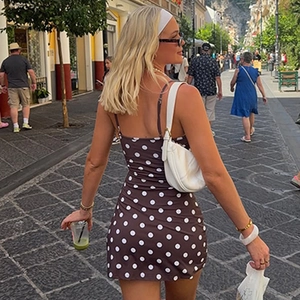Vue de rue d'une robe mini moulante à pois marron avec de fines bretelles