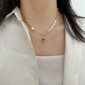 Detail of asymmetric pearl necklace with golden floral pendant and diamond accents