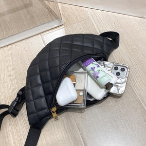Internal view of black quilted waist bag showing large capacity for phone and cosmetics