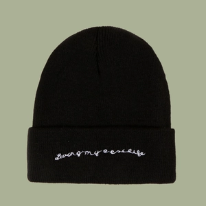 Detailed close-up of Living my best life white embroidery on a black knitted beanie hat