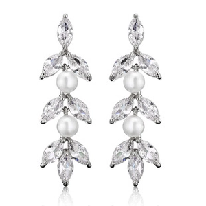 Détail de boucles d'oreilles argentées en C avec zircons marquise et perles blanches
