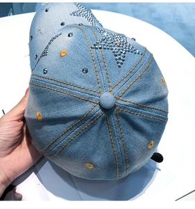 Detail der hellblauen Denim-Baseballkappe mit Strass-Stern und gelben Nähten