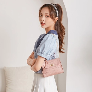 Detail of pink PU leather handbag with embossed cartoon patterns and gold chain strap