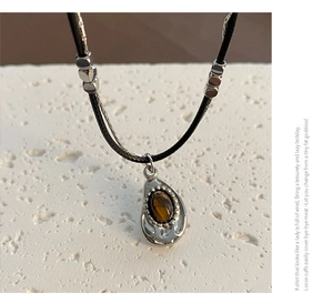 Detailed view of the vintage tiger eye stone pendant on a layered double strand necklace