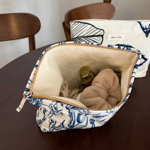 Tie-dye style canvas cosmetic bags with blue leaf print on dark wood table