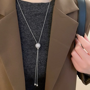 Close-up of a silver Y-necklace with a sparkling crystal ball slide and sleek tassels
