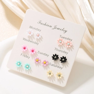 Close-up of 7 pairs of colorful daisy flower stud earrings on a weekly organizer card
