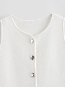 Gros plan sur le gilet en tricot blanc avec trois boutons métalliques argentés irréguliers