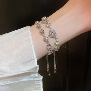 Detailed view of adjustable silver bracelets with pink heart zircon stones on model wrist