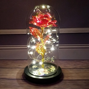 Detail of red gold foil rose in a glass dome with warm LED fairy lights on black base
