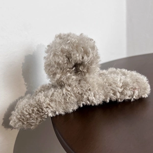 Detail shot of plush faux fur shark hair claw clip in beige on a wooden background