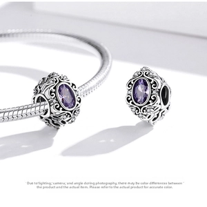 Macro detail of a vintage silver charm with faceted purple zircon on a snake chain