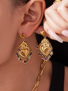 Gros plan de boucles d'oreilles cœur vintage en or avec glands de perles colorées
