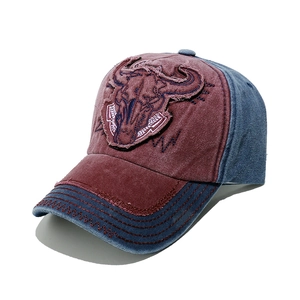 Close-up of vintage distressed denim baseball cap featuring bull skull patch and worn edges