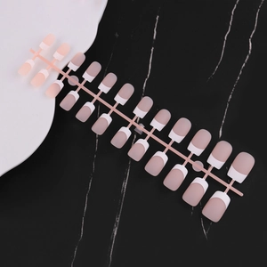 Macro view of 24pcs matte French tip press-on nails in nude pink on a black marble base