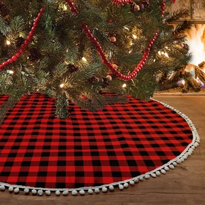 Detail eines rot-schwarz karierten Weihnachtsbaumrockes mit weißen Pompon-Fransen-Besatz
