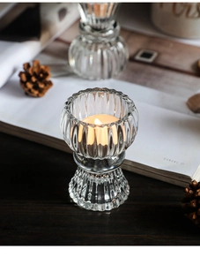 Detailed view of a ribbed glass candle holder with a lit tealight on a wooden table