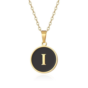 Dettaglio macro della collana placcata oro con ciondolo tondo nero e lettera maiuscola I