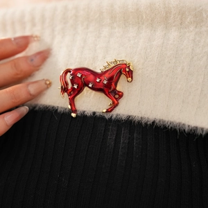 Detail of vintage red enamel horse brooch with rhinestones pinned on knitwear
