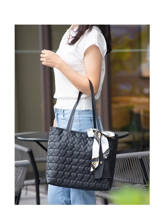 Close-up of black tote bag featuring heart embroidery and decorative silk scarf handles