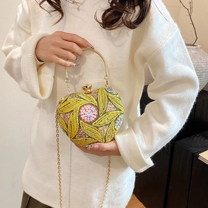 Detail of heart-shaped handbag with yellow leaf embroidery and gold chain strap