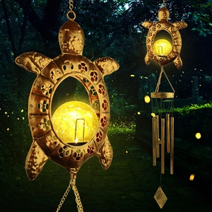 Macro view of turtle solar wind chime with glowing warm yellow sphere in night garden