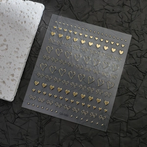 Detailed view of gold bow and heart nail art stickers on a decorative stone base
