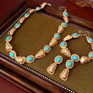 Détail macro d'une parure vintage dorée avec pierres turquoises sur plateau en bois