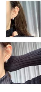 Detail of silver hoop earrings with smiley face pattern worn by a model in profile