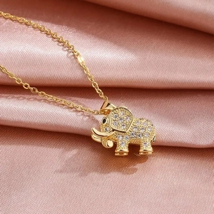 Collier éléphant doré minimaliste serti de cristaux posé sur un tissu de soie rose