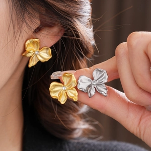 Detailed view of floral stud earrings with metallic petals and sparkling rhinestone centers