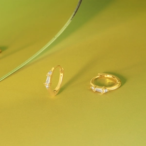 Detail of gold huggie earrings with rectangle center stone and white zircon accents