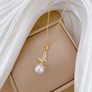 Close-up of golden butterfly pendant with sparkling crystals and white pearl drop