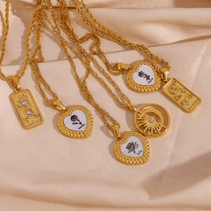 Macro shot of 18K gold plated tarot pendants and heart charms on silk background