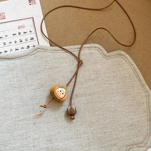 Close-up of vintage handmade round pendant with cute doll face on brown braided cord