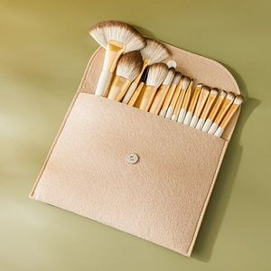 Set of 13 professional makeup brushes with gold wood handles in a beige felt pouch